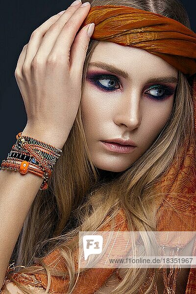 Beautiful fashion girl in a scarf and bracelets boho style. Beauty face  bright trendy makeup. Picture taken in the studio