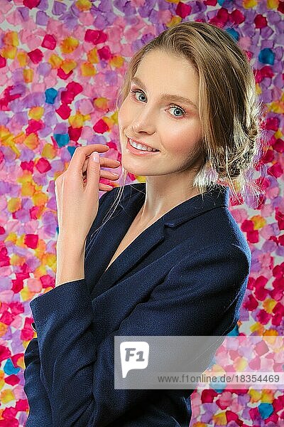 Porträt eines hübschen Mädchens in klassischer Jacke  die ihre Hände auf einem lebhaften Blumenhintergrund klatscht