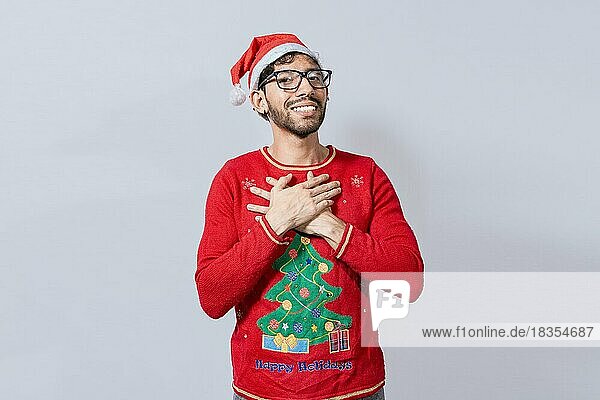 Dankbare Menschen in weihnachtlicher Kleidung lächelnd mit Händen auf der Brust. Mann in Weihnachtsmütze mit aufrichtigen schönen Lächeln Gefühl dankbar  Lächelnde Kerl in Weihnachtsmütze machen danke Geste