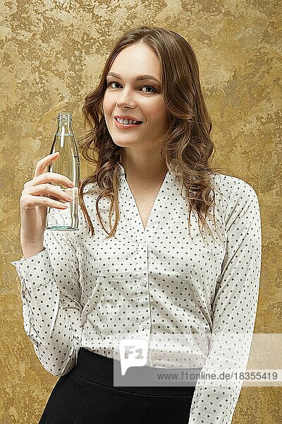 Porträt eines attraktiven lächelnden Mädchens mit einer Flasche Wasser in der Hand