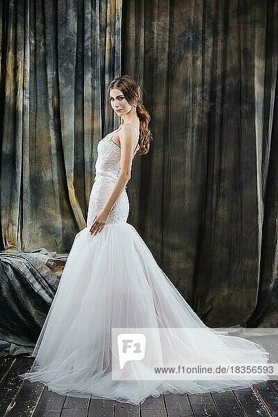 Full length portrait of pretty bride in wedding dress in profile