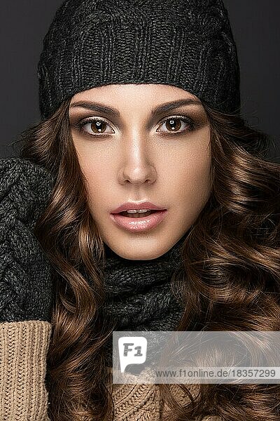 Schönes Mädchen mit Smokey-Make-up  Locken in schwarzer Winter-Strickmütze. Warmes Winterbild. Schönes Gesicht. Bild im Studio aufgenommen