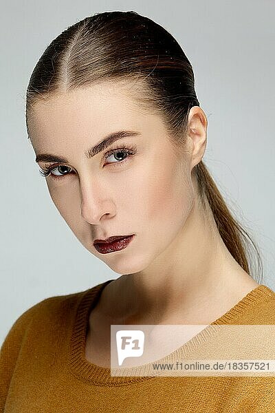 Closeup portrait of a girl with perfect skin  dark matt lipstick and smooth slick hair