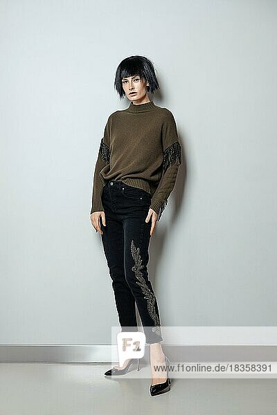 Modemodell mit schwarzer Perücke  Pullover mit Fransen und Jeans mit Strasssteinen