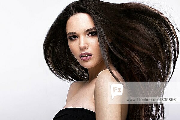 Beautiful brunette girl in move with a perfectly smooth hair  and classic make-up. Beauty face. Picture taken in the studio on a white background