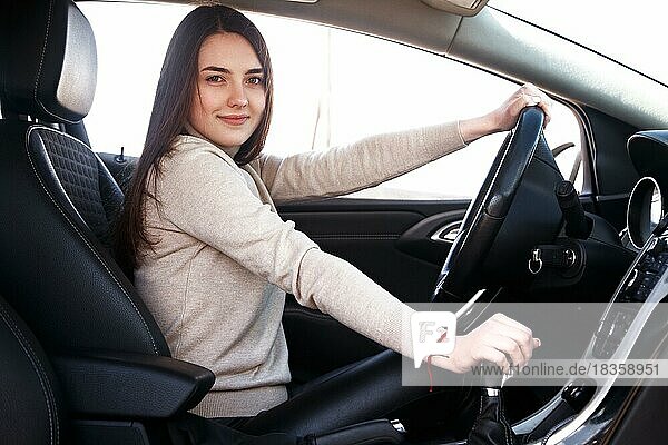 Junge schöne glückliche Frau sitzt am Steuer eines neuen Autos