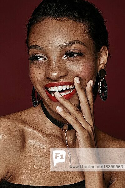 Schöne schwarze Frau mit einem Lächeln und roten Lippen und Sommersprossen. Schönes Gesicht. Foto im Studio aufgenommen