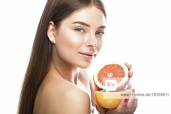 Schönes junges Mädchen mit einem leichten natürlichen Make-up und perfekter Haut mit Grapefruit in der Hand. Schönes Gesicht. Bild im Studio auf einem weißen Hintergrund aufgenommen