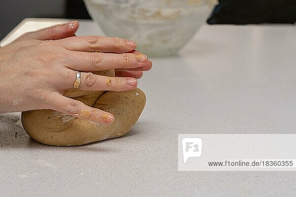 Nahaufnahme von Frauenhänden  die in ihrer Küche frischen Teig für die Herstellung von Keksen kneten