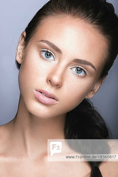 Schönes junges Mädchen mit einem leichten natürlichen Make-up. Schönes Gesicht. Bild im Studio auf einem grauen Hintergrund aufgenommen