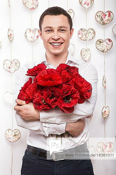 Schöner verliebter junger Mann mit einem Blumenstrauß. Valentinstag. Bild im Studio aufgenommen