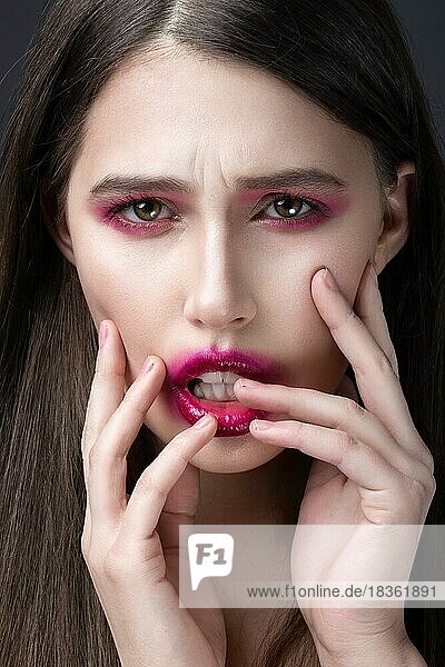 Mädchen mit rosa Lippenstift im Gesicht verschmiert. Kreatives Make-up. Bild im Studio aufgenommen