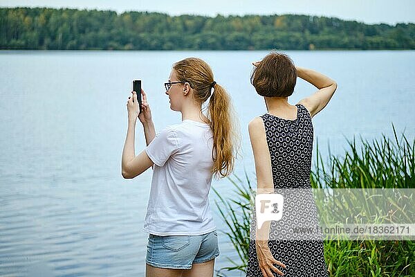 Mother and daughter have come to the shore of the lake and are exploring the surroundings