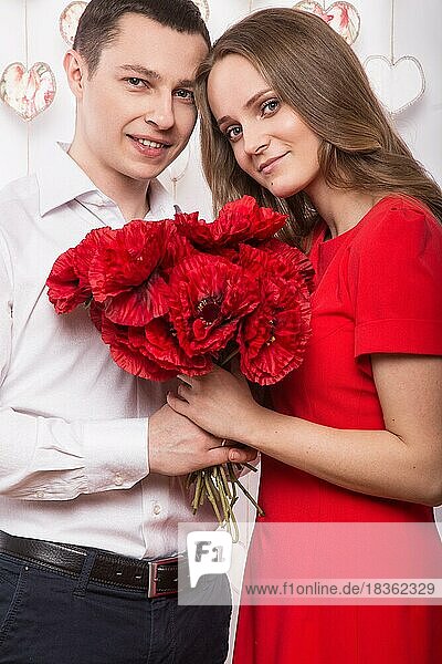 Schönes junges verliebtes Paar mit einem Blumenstrauß. Valentinstag. Bild im Studio aufgenommen