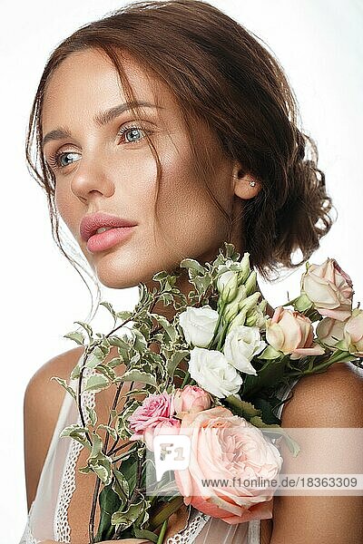 Schöne Frau mit klassischem Nackt-Make-up  heller Frisur und Blumen. Schönes Gesicht. Foto im Studio aufgenommen