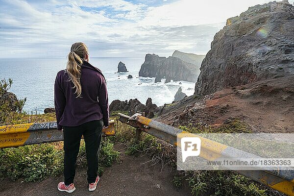 Junge Frau schaut aufs Meer  Miradouro da Ponta do Rosto  zerklüftete Küste mit Felsformationen  Kap Ponta de São Lourenço  Madeira  Portugal  Europa