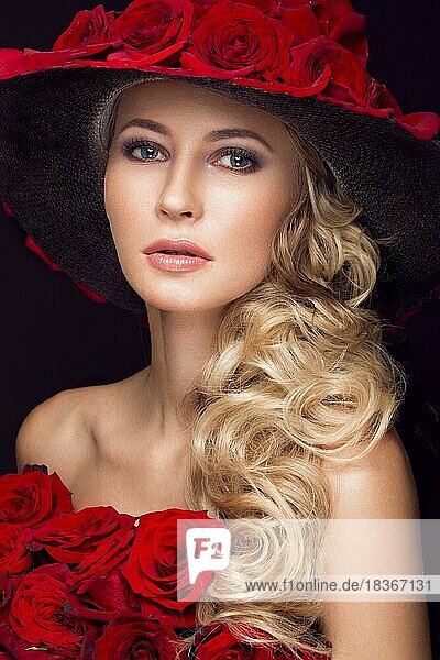 Schönes blondes Mädchen in einem Kleid und Hut mit Rosen  klassischem Make-up  Locken und roten Lippen. Schönes Gesicht. Fotos im Studio aufgenommen