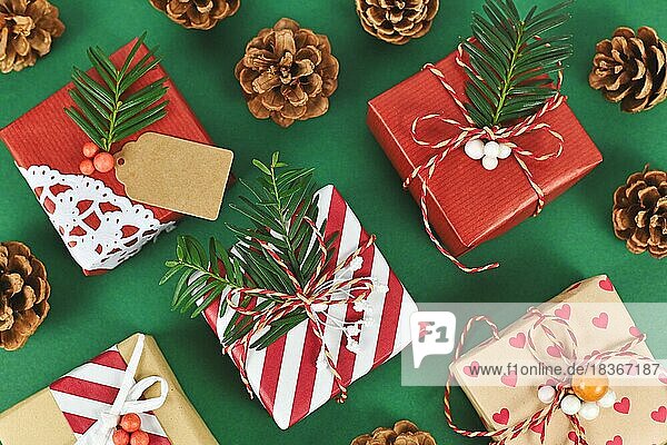 Draufsicht auf schöne rot  weiß und natürlich braun dekoriert Weihnachtsgeschenk-Boxen mit Bändern und Tannenzweigen auf grünem Hintergrund