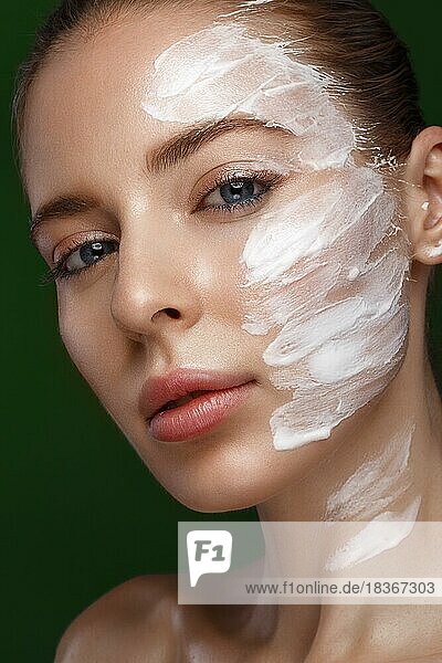 Schönes frisches Mädchen mit kosmetischer Creme auf dem Gesicht  natürliches Make-up. Schönes Gesicht. Foto im Studio aufgenommen