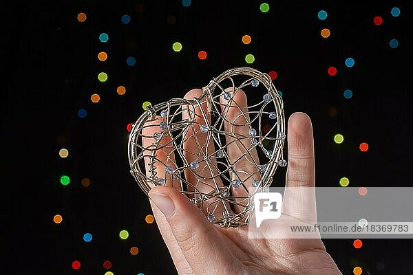 Herzförmigen Metallkäfig in der Hand auf Bokeh Licht Hintergrund