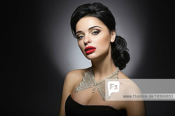 Beautiful woman with evening make-up  red lips and evening hairstyle. Beauty face. Picture taken in the studio on a gray background