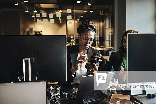 Geschäftsfrau  die im Büro mit ihrem Smartphone im Internet surft