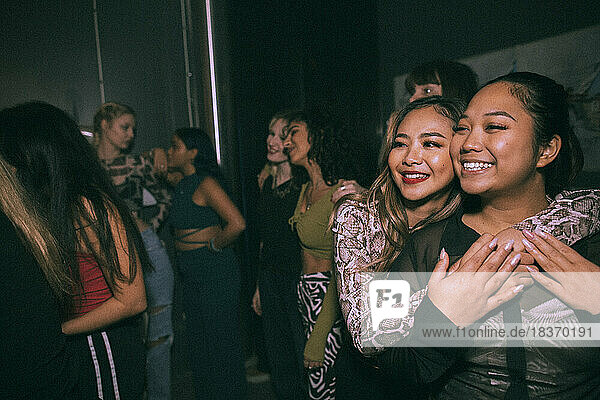 Happy young woman embracing friend enjoying at nightclub