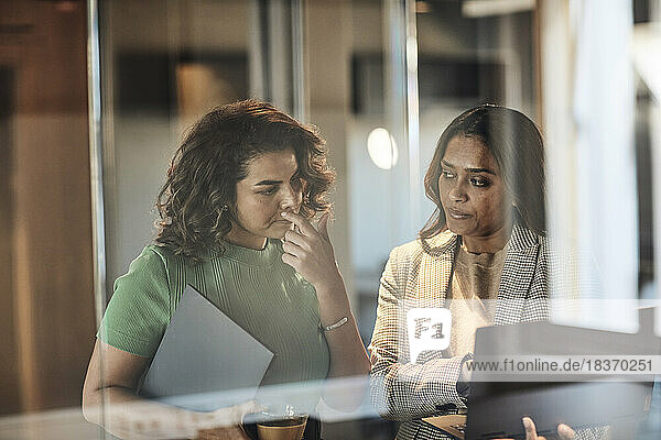 Geschäftsfrau schaut auf den Laptop  den eine Kollegin im Büro hält