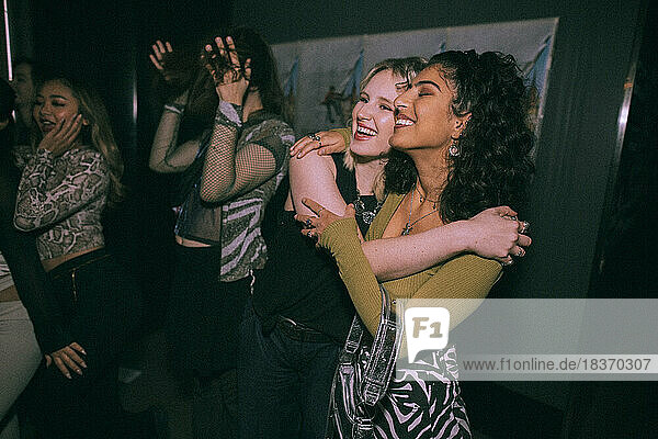 Fröhliche junge Frauen umarmen sich in einem Nachtclub