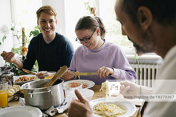 Glückliche Familie genießt das gemeinsame Essen am Esstisch zu Hause