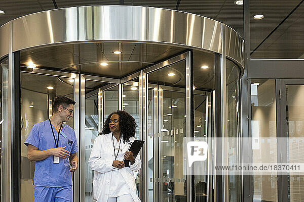 Lächelnde multirassische Ärzte und Ärztinnen vor einer Drehtür