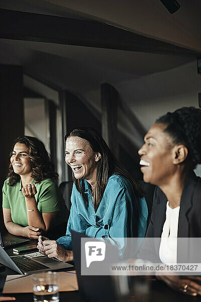 Lachende Unternehmerinnen bei einem Geschäftstreffen im Büro