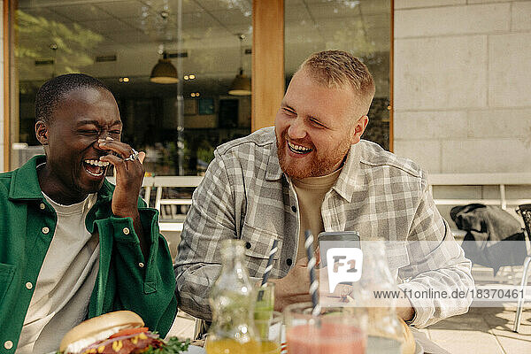 Glückliche multirassische Freunde  die zusammen in einem Straßencafé sitzen