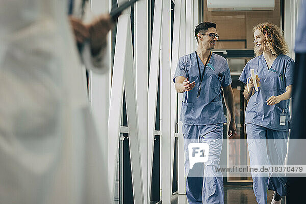 Smiling male and female healthcare staff walking in corridor of hospital