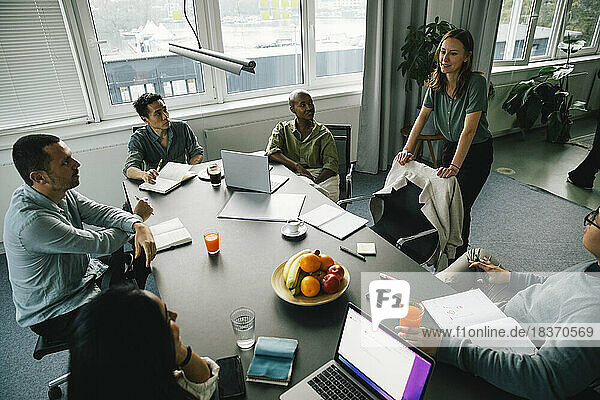 Geschäftsfrau diskutiert in Brainstorming-Sitzung mit multirassischen Kollegen am Schreibtisch im Büro