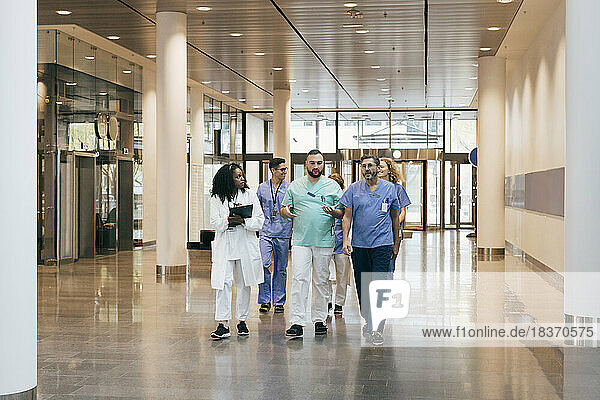 Multirassische Gruppe von männlichen und weiblichen Krankenhausmitarbeitern  die sich in der Lobby unterhalten