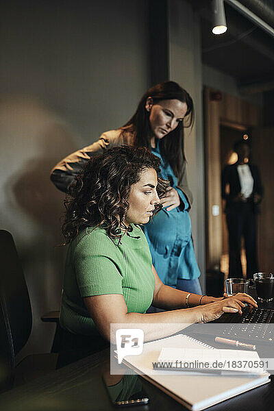Geschäftsfrau arbeitet im Büro mit einer schwangeren Kollegin am Laptop