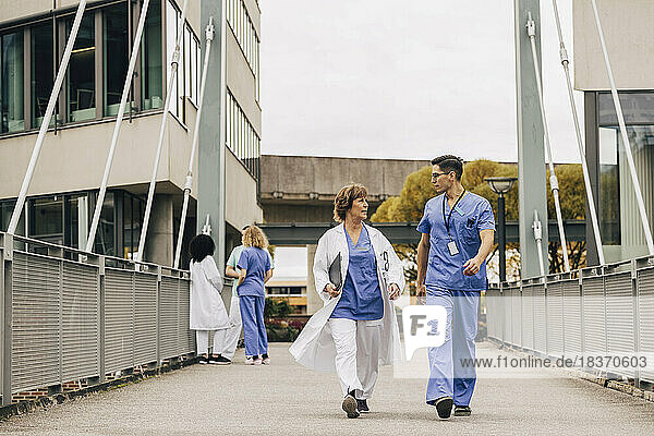 Weiblicher Arzt im Gespräch mit Krankenhauspersonal auf einer Brücke