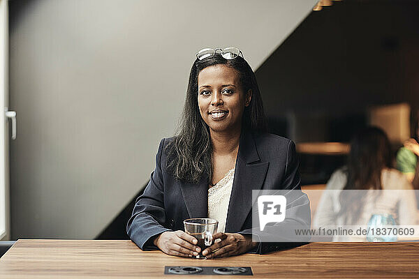 Porträt einer lächelnden reifen Geschäftsfrau mit Kaffeetasse am Schreibtisch im Büro