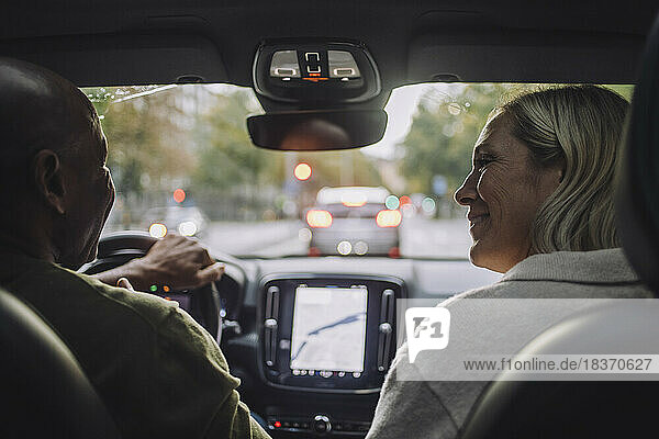 Glückliches reifes Paar  das sich während der Fahrt im Auto unterhält