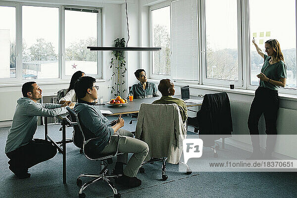 Geschäftsfrau bei einer Besprechung mit Kollegen  die am Schreibtisch im Büro sitzen