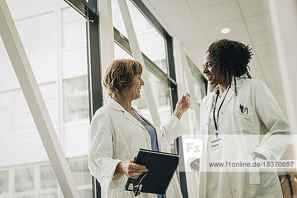 Female physician gesturing while talking with coworker at hospital
