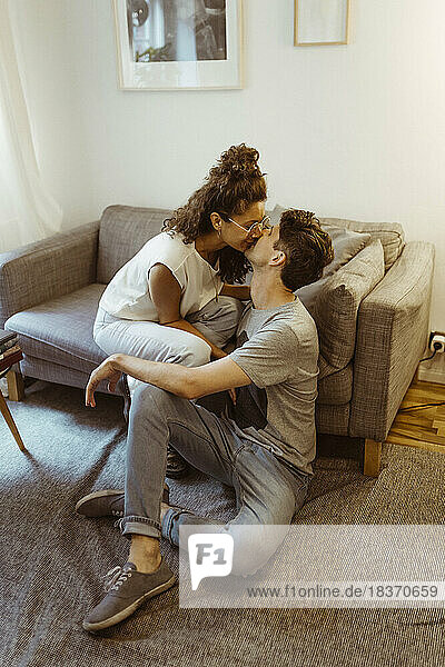 Romantische Freund und Freundin küssen einander sitzen im Wohnzimmer zu Hause