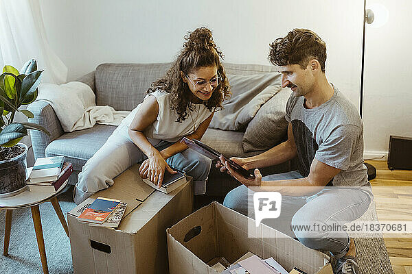 Mann teilt Fotorahmen mit Freundin beim Auspacken von Kartons zu Hause