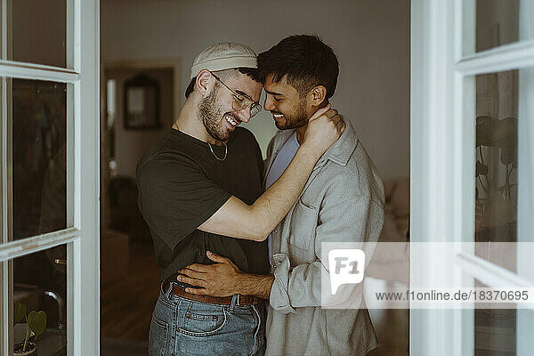 Liebendes homosexuelles Paar  das zu Hause lächelnd beieinander steht