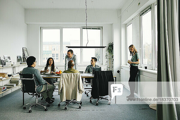 Männliche und weibliche Kollegen unterhalten sich während eines Geschäftstreffens im Büro miteinander