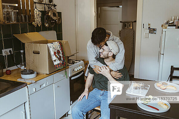 Romantischer Mann umarmt seinen Freund in der Küche zu Hause