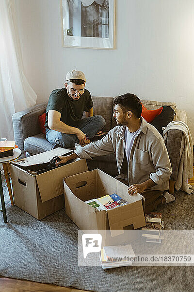 Schwules Paar  das sich beim Auspacken von Kartons zu Hause unterhält