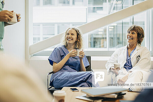 Glückliche weibliche Angestellte des Gesundheitswesens beim Kaffee in der Pause im Krankenhaus