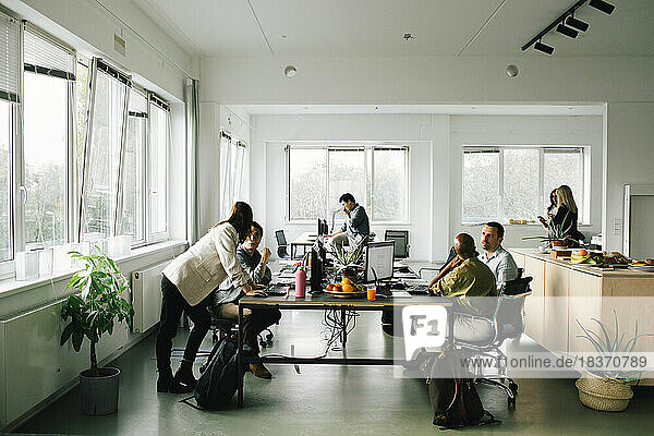 Geschäftskollegen  die am Schreibtisch sitzend im Büro diskutieren und planen